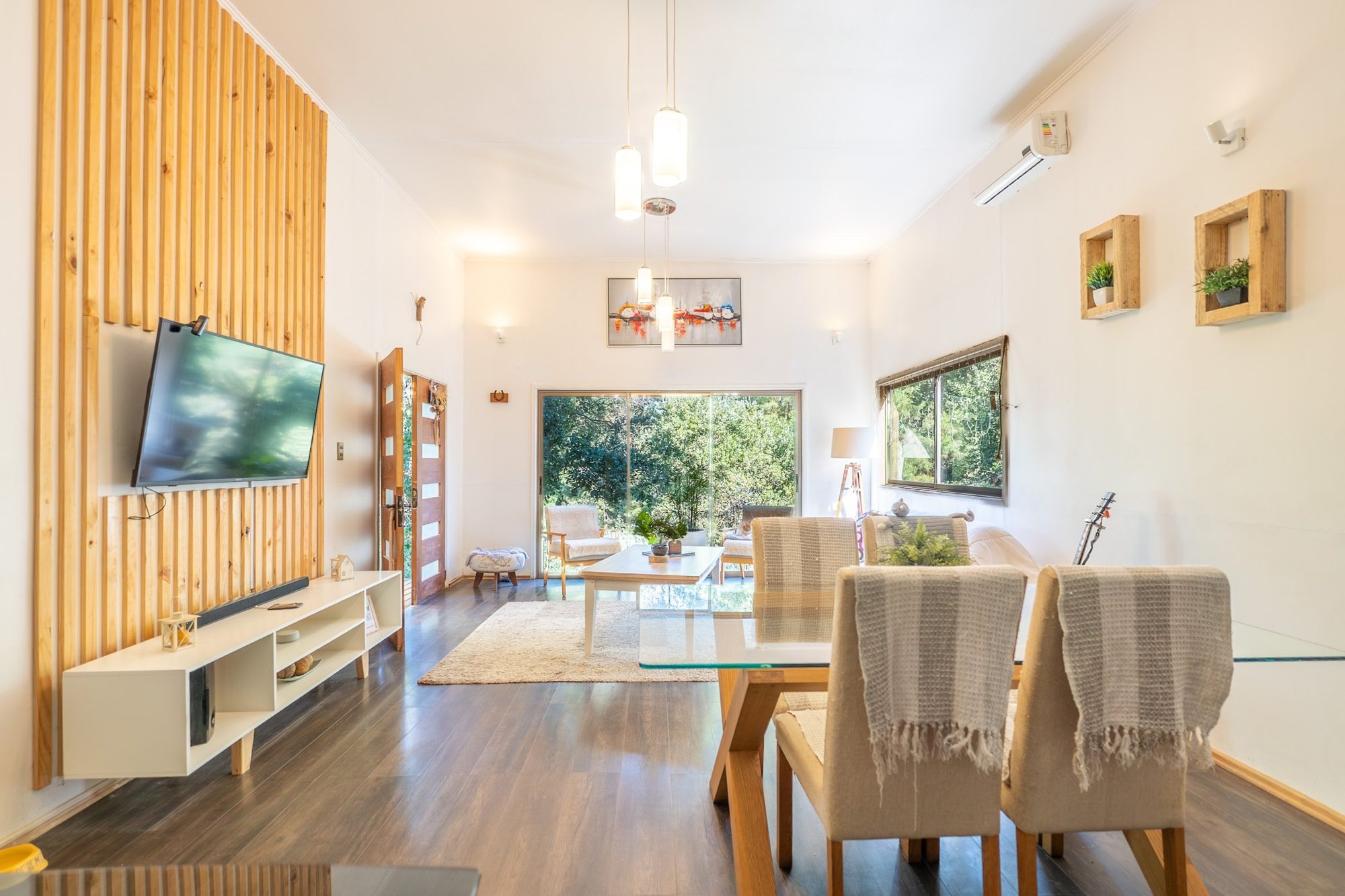 Living comedor luminoso con muro de listones de madera y ventanal al jardín